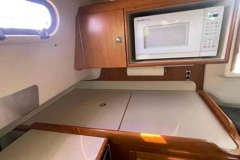 Slide: The Image of 2013 Catalina Morgan 440 yacht interior kitchen with microwave and wooden cabinetry. - 35
