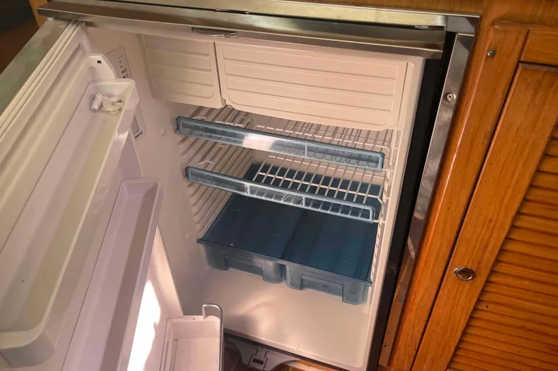 Slide: The Image of Open refrigerator inside a 2013 Catalina Morgan 440 yacht, featuring empty shelves and wooden cabinetry. - 39