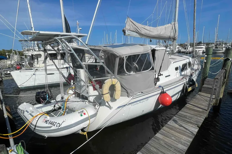 Slide: The Image of 2013 Catalina Morgan 440 sailboat docked at marina with dinghy attached. - 92
