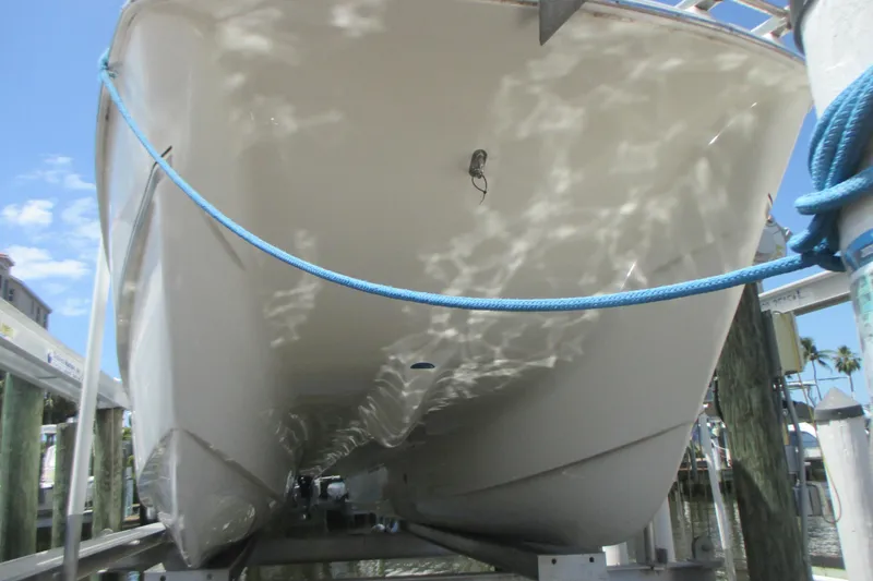 Slide: The Image of 2020 World Cat 230 SD boat hull on lift, with blue rope and dock background. - 2