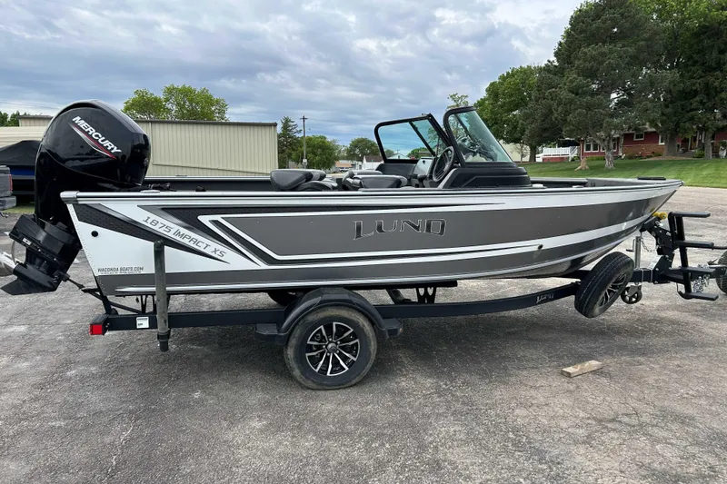 The Image of 2025 Lund 1875 Impact XS Sport boat on trailer, featuring Mercury outboard motor. - 0