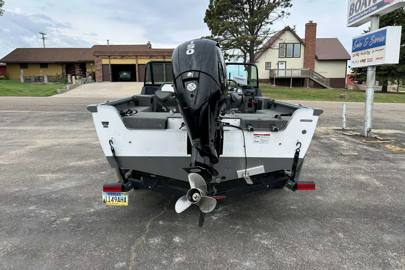 Slide: The Image of 2025 Lund 1875 Impact XS Sport boat with outboard motor, parked in a driveway. - 2