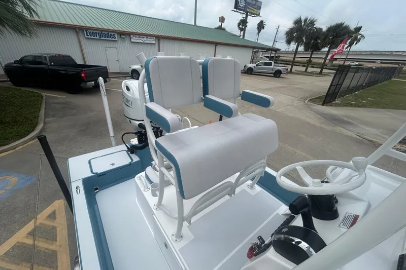 Slide: The Image of 2026 Shallow Sport 22 Sport boat with dual seating and steering wheel, parked outdoors. - 11