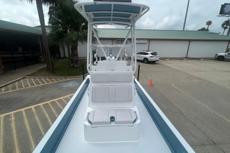 Slide: The Image of 2026 Shallow Sport 22 Sport boat with seating, parked outdoors near palm trees. - 8