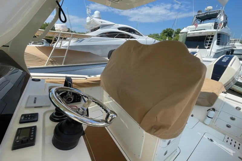 Slide: The Image of 2023 Scout 305 LXF boat helm with covered seat, docked near luxury yachts. - 10