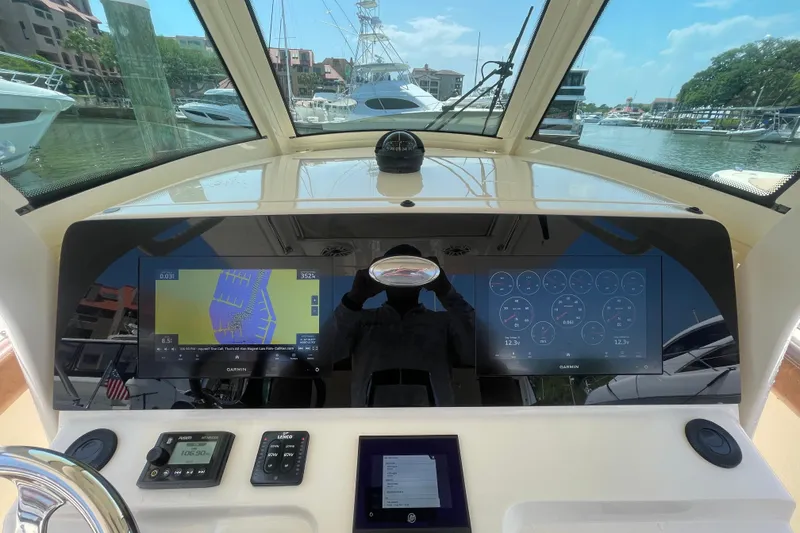 Slide: The Image of 2023 Scout 305 LXF boat dashboard with navigation and control displays in a marina setting. - 13