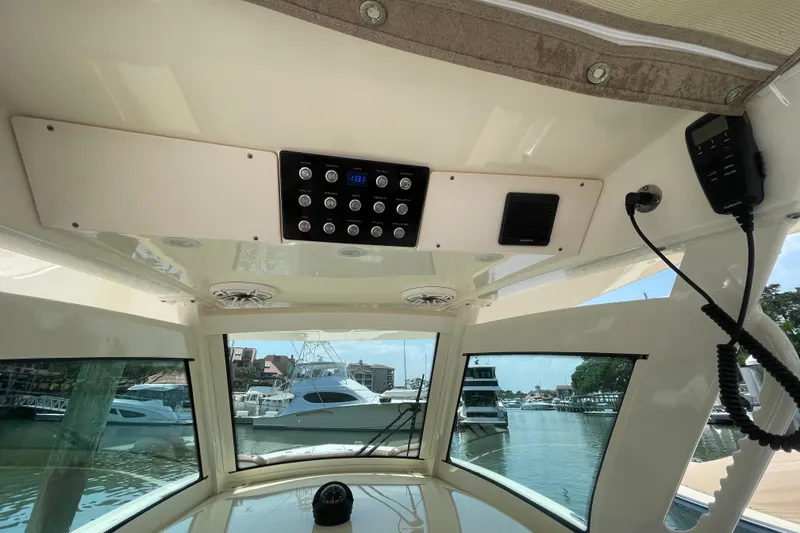 Slide: The Image of Interior view of 2023 Scout 305 LXF boat dashboard with control panel and marina background. - 16