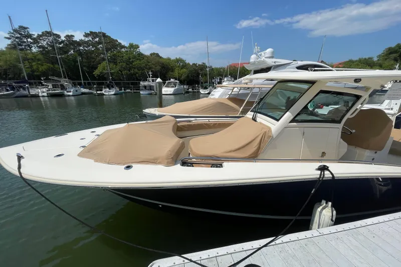 Slide: The Image of 2023 Scout 305 LXF boat docked in a marina with protective covers. - 2