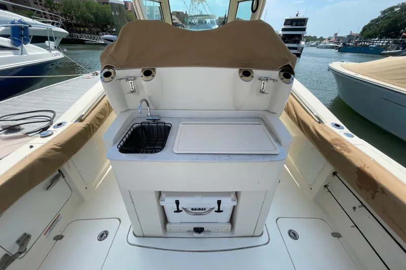 Slide: The Image of 2023 Scout 305 LXF boat interior with sink and storage, docked at marina. - 21