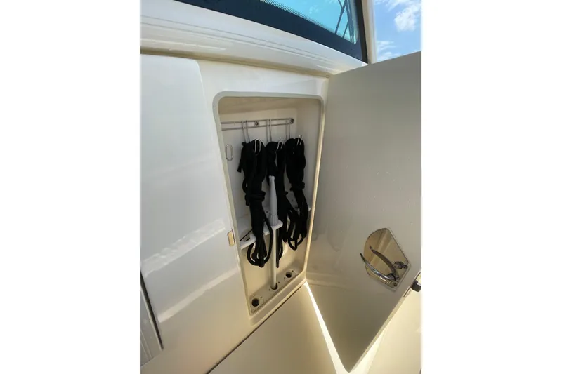 Slide: The Image of Storage compartment on 2023 Scout 305 LXF boat, featuring neatly organized black straps. - 24