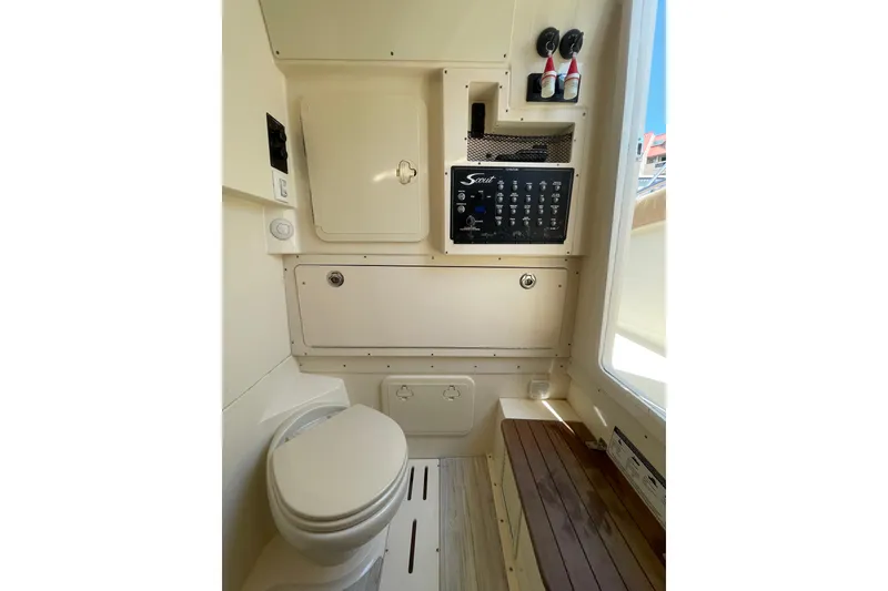 Slide: The Image of 2023 Scout 305 LXF boat interior with toilet, control panel, and storage compartments. - 26
