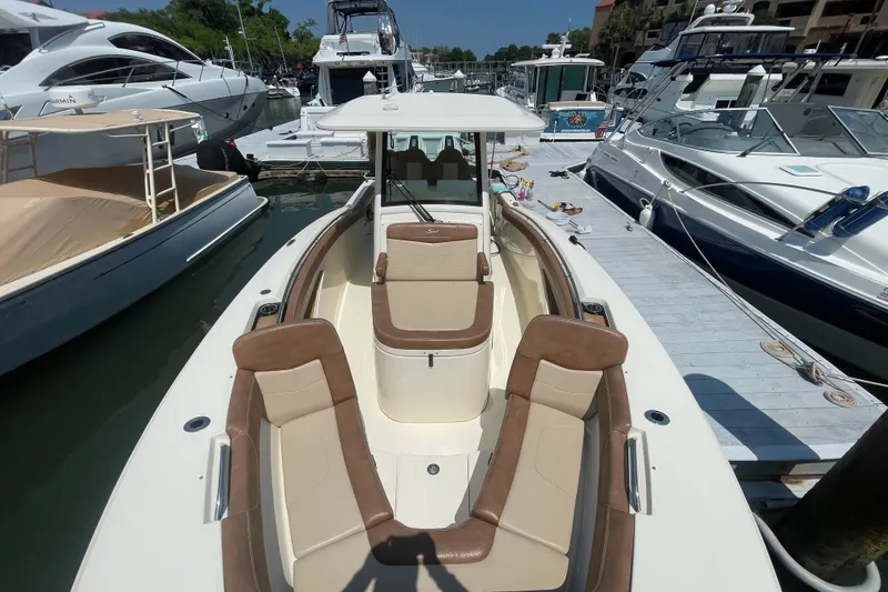 Slide: The Image of 2023 Scout 305 LXF boat docked at marina, featuring spacious seating and sleek design. - 5