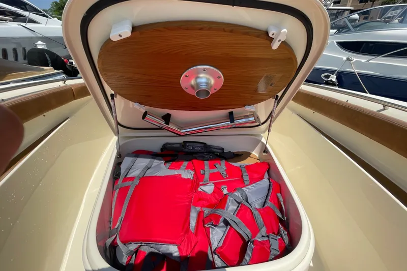 Slide: The Image of Open storage compartment on 2023 Scout 305 LXF boat with red life jackets inside. - 9