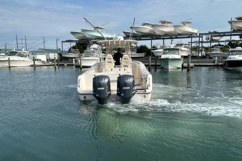 Slide: The Image of 2016 Grady-White Canyon 306 boat navigating marina waters, surrounded by docked vessels. - 2