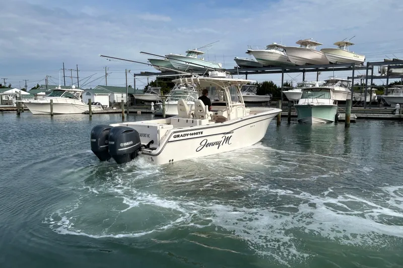 Slide: The Image of 2016 Grady-White Canyon 306 boat navigating marina waters with docked vessels. - 3