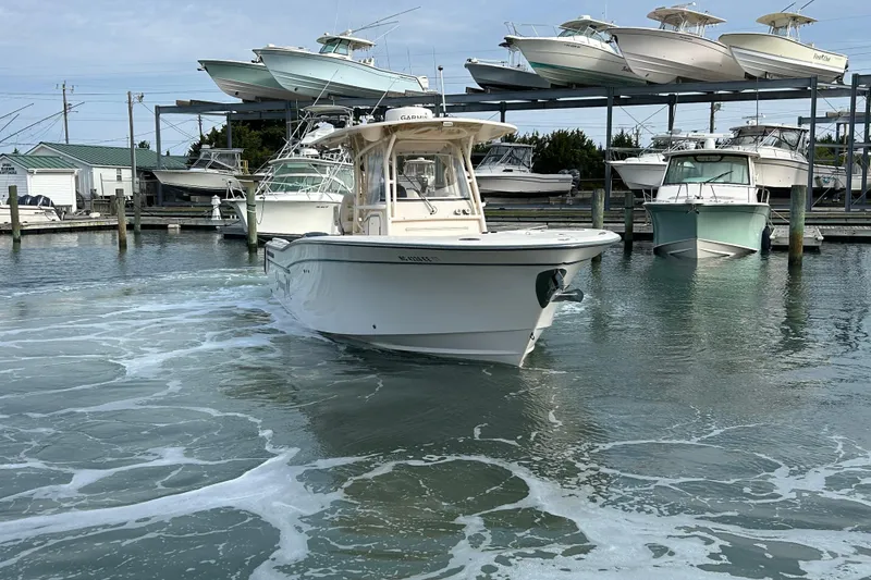 Slide: The Image of 2016 Grady-White Canyon 306 boat navigating marina waters, surrounded by docked vessels. - 6