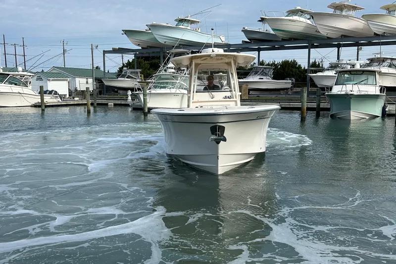 Slide: The Image of 2016 Grady-White Canyon 306 boat navigating marina waters, surrounded by docked vessels. - 7