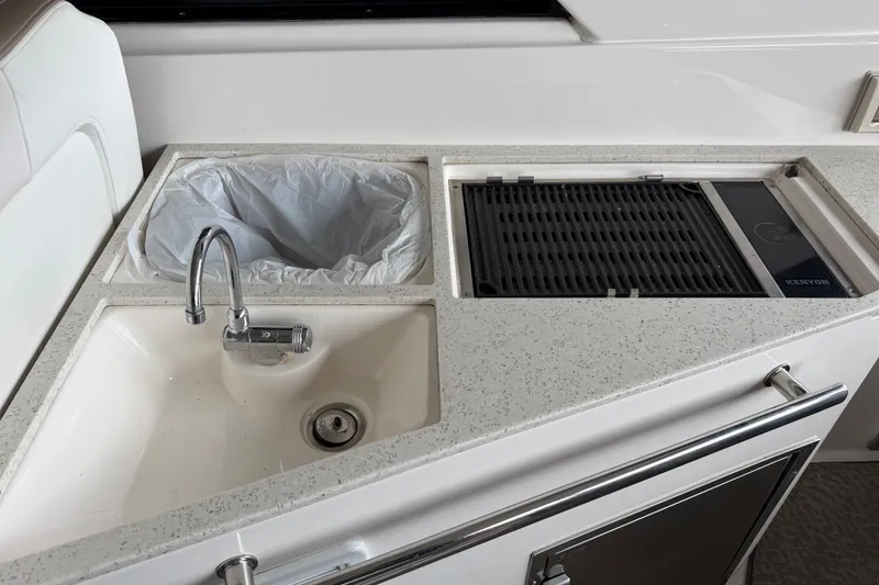 Slide: The Image of 2016 Regal 35 Sport Coupe yacht kitchenette with sink, grill, and trash compartment. - 15