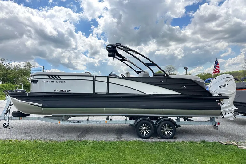 The Image of 2024 Bennington LX Sport Line pontoon boat on trailer under cloudy sky. - 0