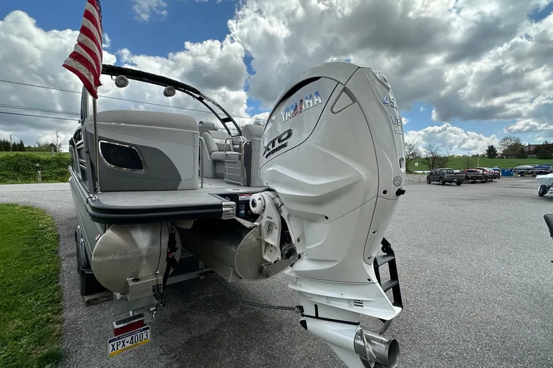 Slide: The Image of 2024 Bennington LX Sport Line boat with Yamaha outboard motor, parked outdoors under cloudy sky. - 10