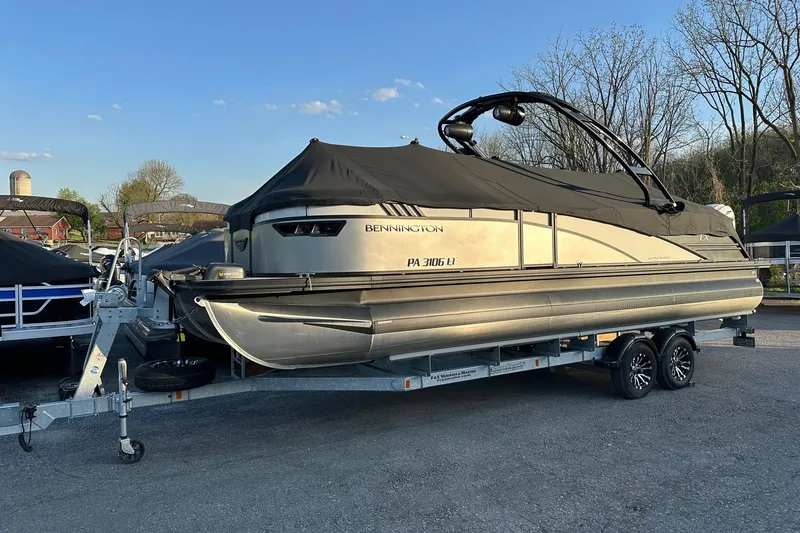 Slide: The Image of 2024 Bennington LX Sport Line pontoon boat on trailer, covered and parked outdoors. - 3