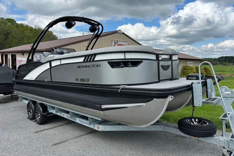 Slide: The Image of 2024 Bennington LX Sport Line pontoon boat on trailer, parked outdoors under cloudy sky. - 5