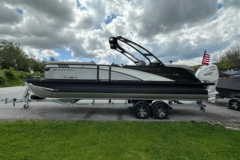 Slide: The Image of 2024 Bennington LX Sport Line pontoon boat on trailer under cloudy sky. - 7