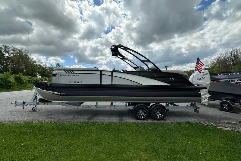 Slide: The Image of 2024 Bennington LX Sport Line pontoon boat on trailer under cloudy sky. - 8