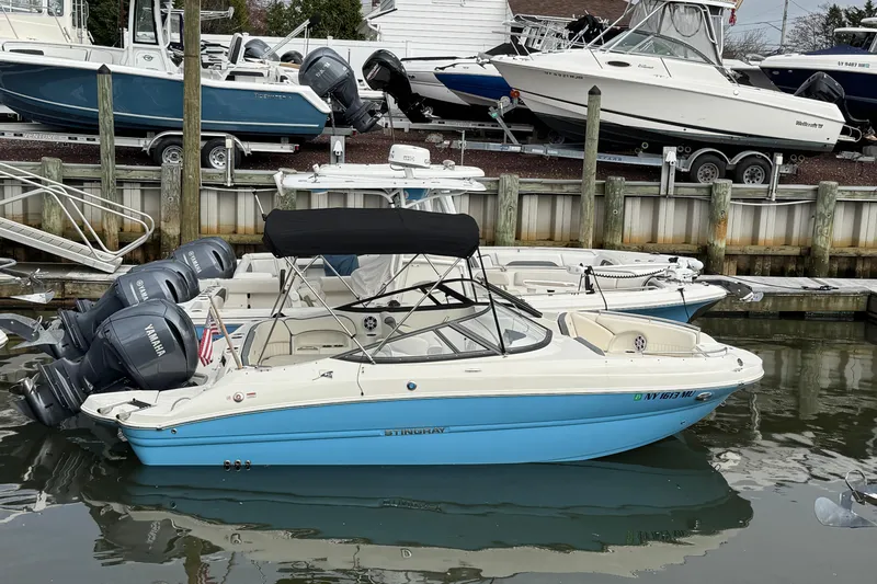 The Image of 2024 Stingray 211 DC boat docked, featuring Yamaha engines and a sleek blue and white design. - 0
