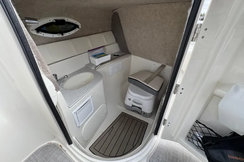 Slide: The Image of 2024 Stingray 211 DC boat interior with compact bathroom, sink, and toilet. - 15