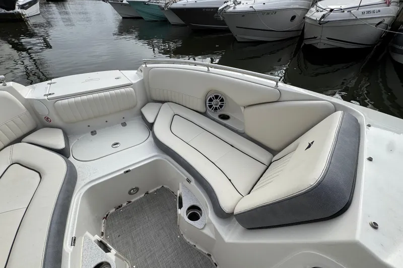 Slide: The Image of 2024 Stingray 211 DC boat interior with white cushioned seating and cup holders at a marina. - 17