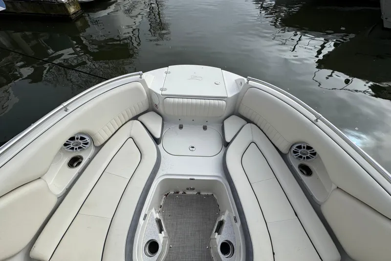 Slide: The Image of 2024 Stingray 211 DC boat interior with white seating and cup holders on water. - 19