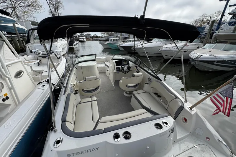 Slide: The Image of 2024 Stingray 211 DC boat with seating, docked among other boats. - 2