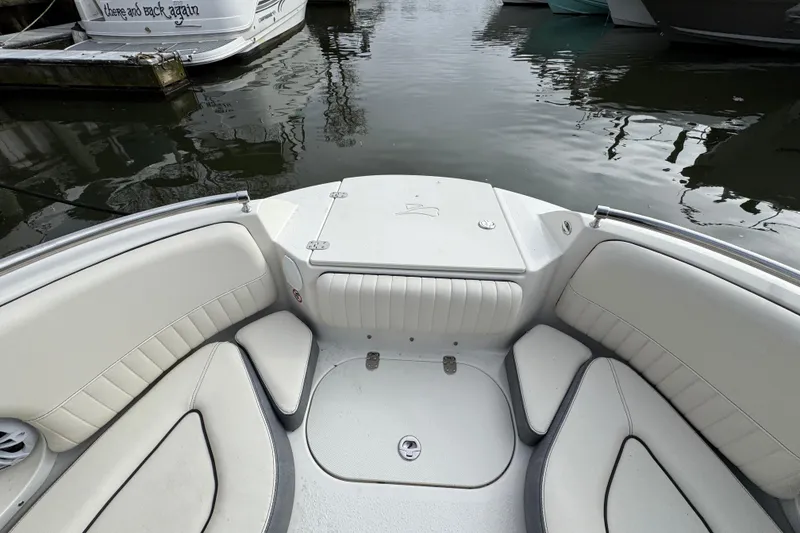 Slide: The Image of 2024 Stingray 211 DC boat interior with white seating, docked near water. - 20