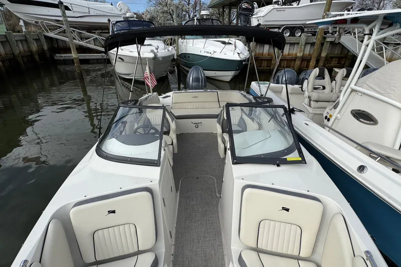 Slide: The Image of 2024 Stingray 211 DC boat docked, featuring spacious seating and sleek design. - 22