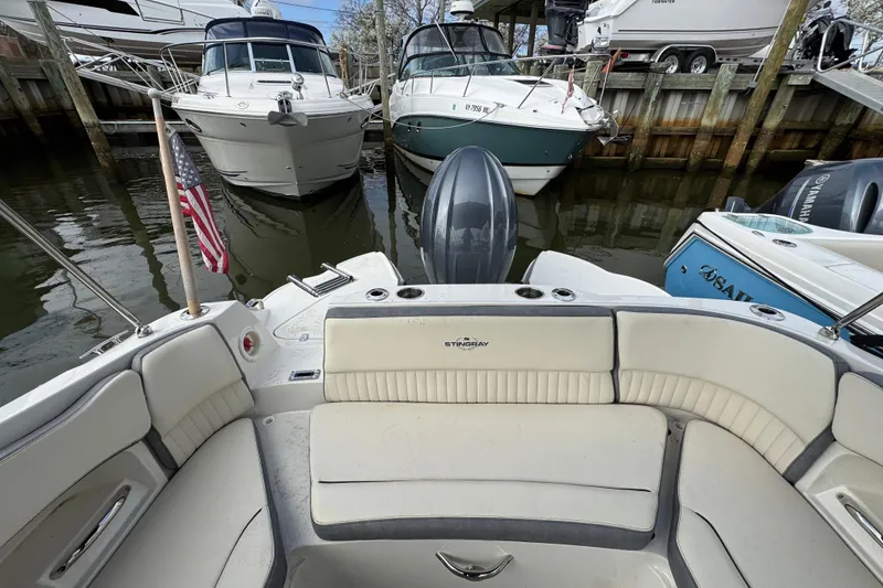 Slide: The Image of 2024 Stingray 211 DC boat docked, featuring spacious seating and American flag. - 3