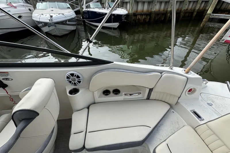 Slide: The Image of 2024 Stingray 211 DC boat interior with white seating and cup holders at a marina. - 4