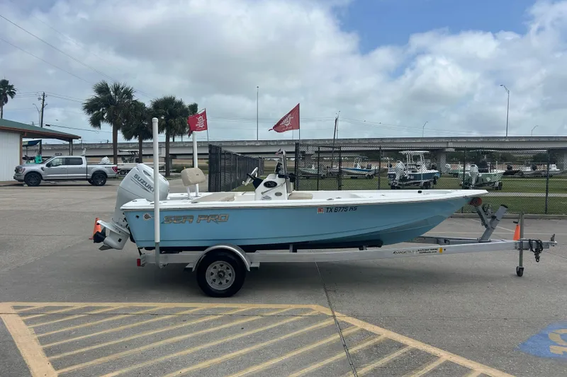 Slide: The Image of 2022 Sea Pro 172 Bay boat on trailer in parking lot, cloudy sky background. - 2