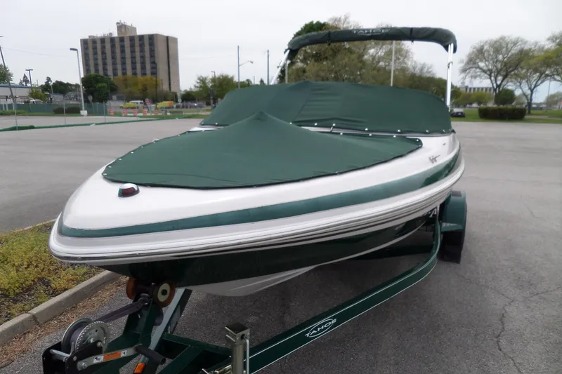 Slide: The Image of 2005 Tahoe Q4 Sport boat with green cover on trailer in parking lot. - 4