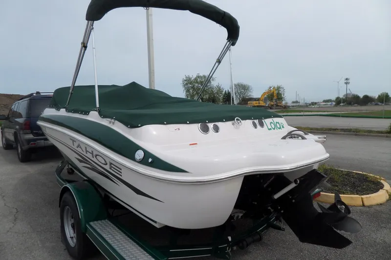 Slide: The Image of 2005 Tahoe Q4 Sport boat with green cover on trailer in parking lot. - 6