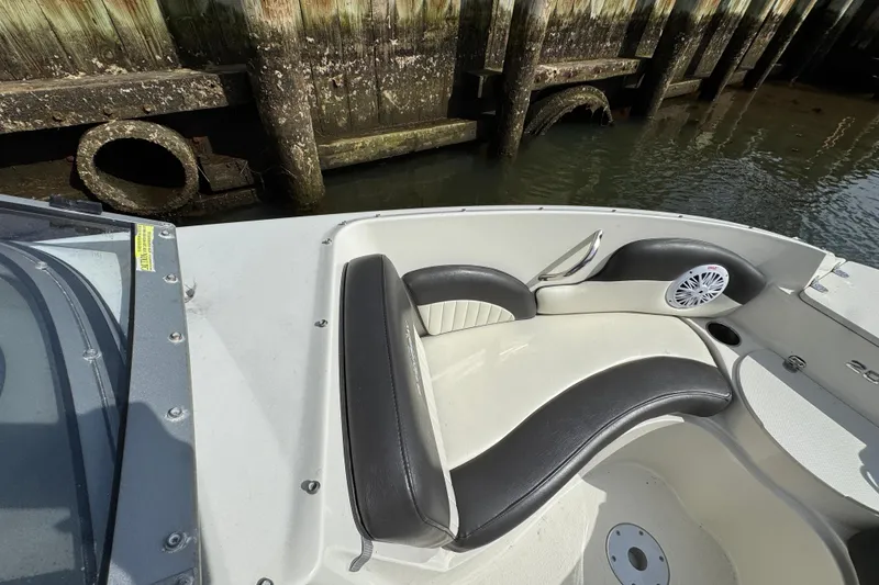 Slide: The Image of 2019 Stingray 204 LR boat interior with black and white seating near a wooden dock. - 12