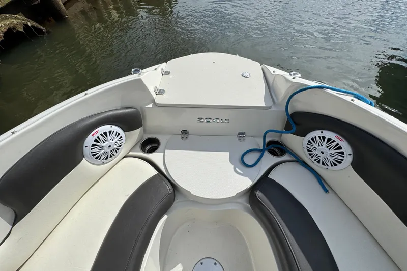 Slide: The Image of 2019 Stingray 204 LR boat interior with speakers and seating by the water. - 14