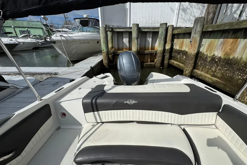 Slide: The Image of 2019 Stingray 204 LR boat docked, featuring sleek seating and outboard motor. - 19