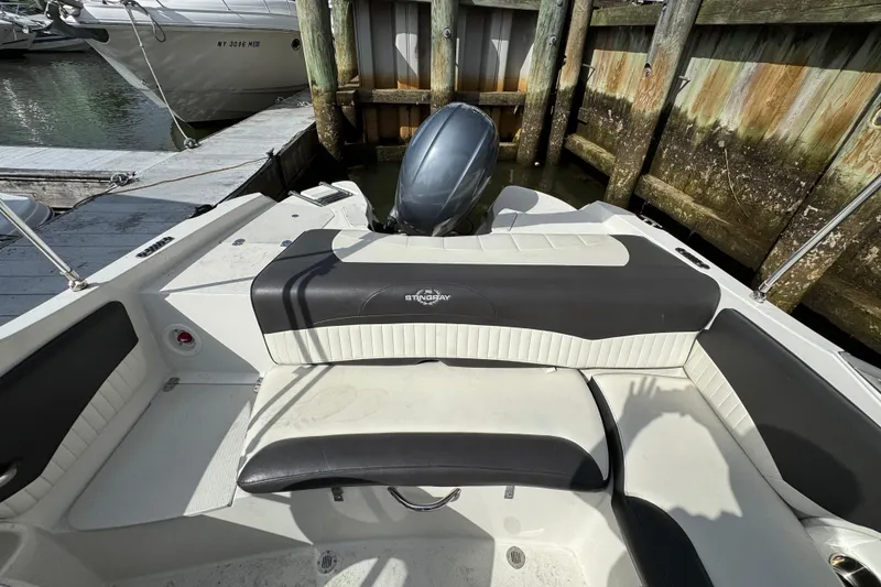 Slide: The Image of 2019 Stingray 204 LR boat interior with seating and motor, docked by wooden pier. - 4