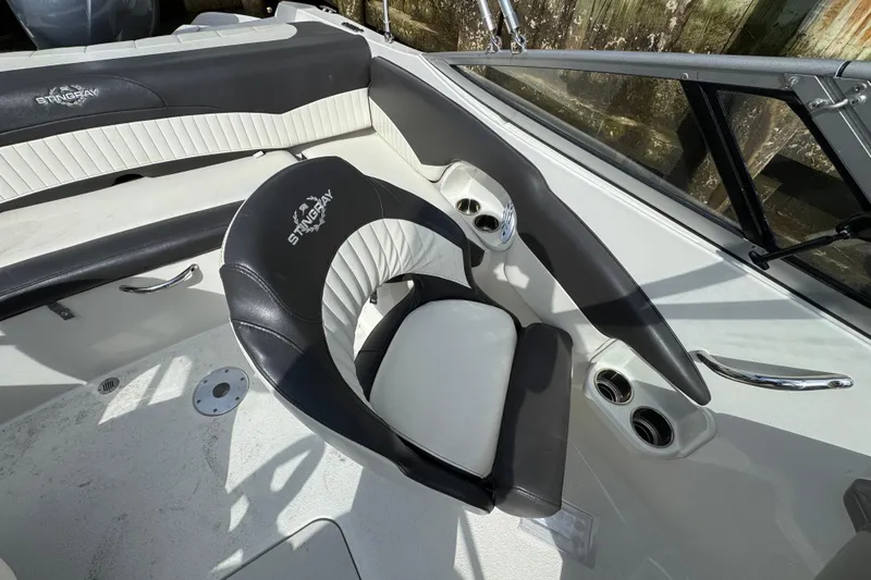 Slide: The Image of 2019 Stingray 204 LR boat interior with black and white seating and cup holders. - 7