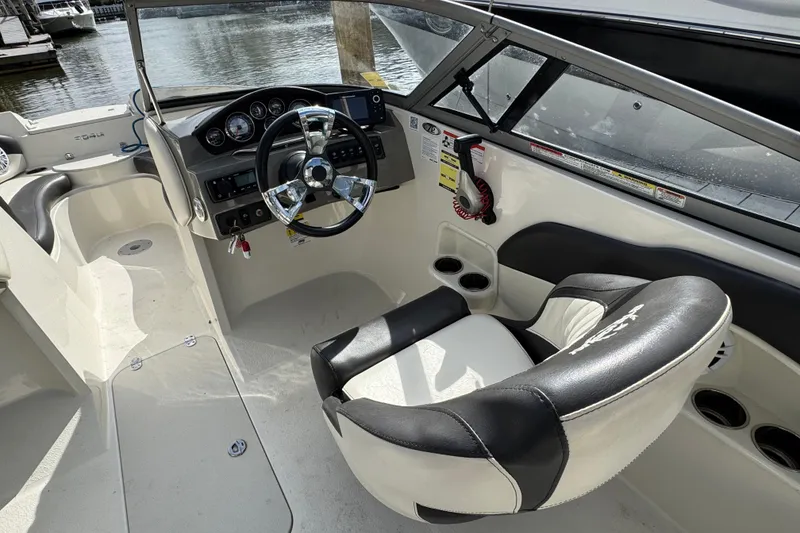 Slide: The Image of 2019 Stingray 204 LR boat interior with steering wheel and dashboard, docked by the water. - 9