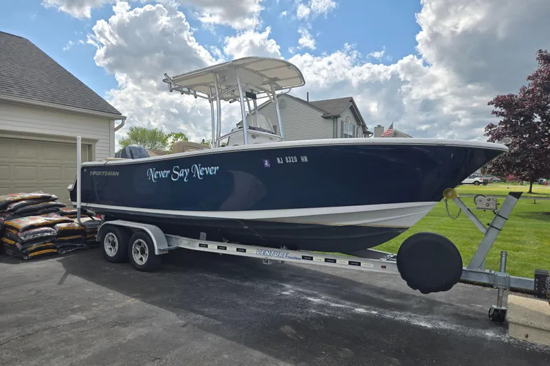 Slide: The Image of 2018 Sportsman Heritage 231 Center Console boat on trailer, parked in driveway under cloudy sky. - 5