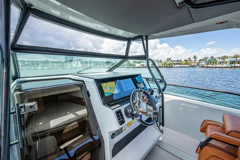 Slide: The Image of 2023 Saxdor 320 GTO helm with modern controls, overlooking a scenic waterfront. - 18