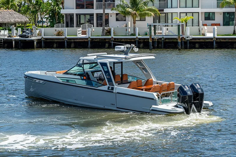 Slide: The Image of 2023 Saxdor 320 GTO boat cruising on a sunny waterfront near modern homes. - 2
