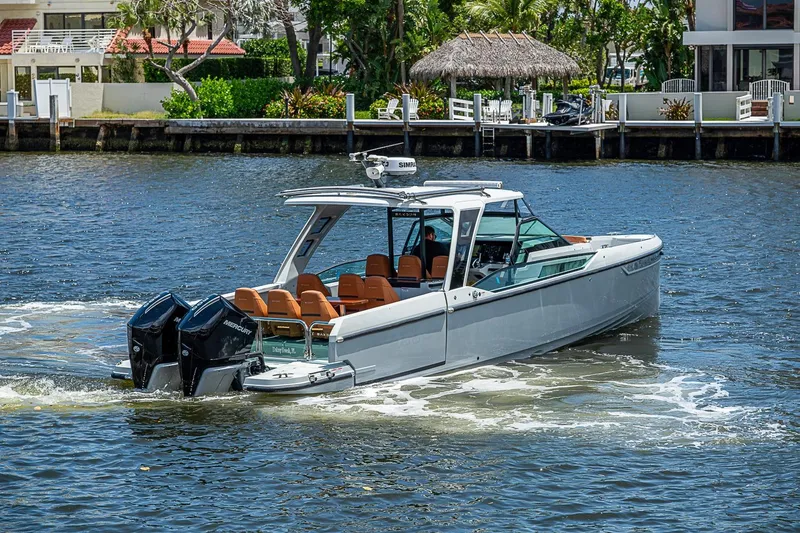 Slide: The Image of 2023 Saxdor 320 GTO boat cruising on a scenic waterway near waterfront homes. - 5